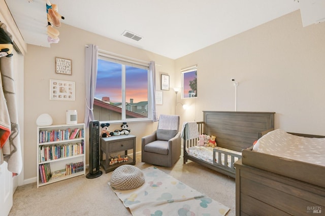 carpeted bedroom featuring visible vents, baseboards, and a nursery area