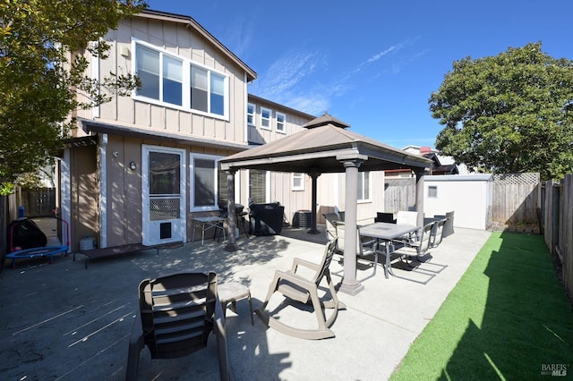back of house with board and batten siding, a fenced backyard, a patio area, a gazebo, and outdoor dining area