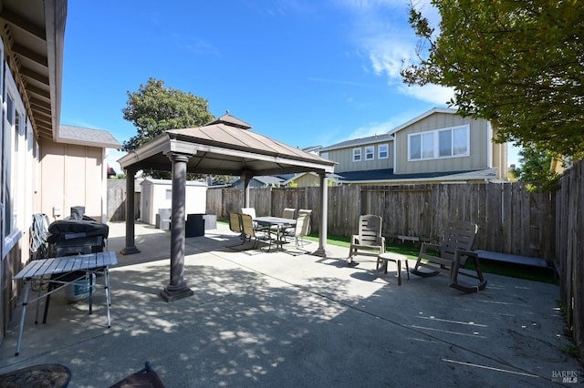 view of patio / terrace featuring outdoor dining space, a fenced backyard, a shed, and an outbuilding