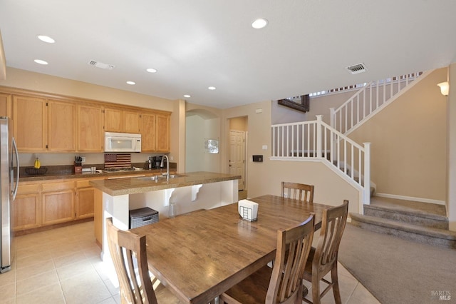 dining area featuring light tile patterned flooring, visible vents, and stairs