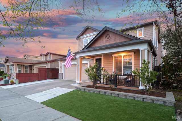 bungalow-style home featuring a front lawn, fence, covered porch, and concrete driveway