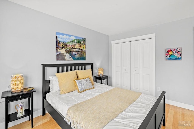 bedroom with baseboards, wood finished floors, and a closet