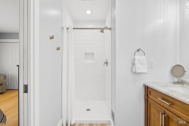 bathroom featuring wood finished floors, vanity, and a stall shower