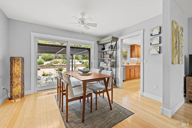 dining room with baseboards, a ceiling fan, and light wood-style floors