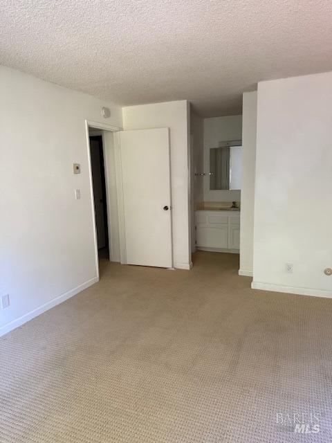 spare room featuring baseboards, light carpet, and a textured ceiling