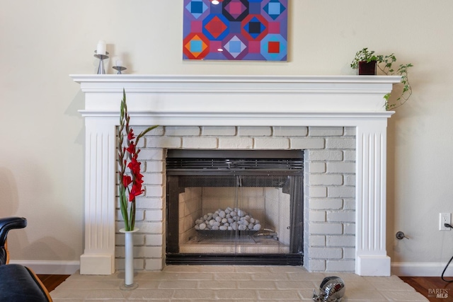 room details featuring baseboards and a brick fireplace