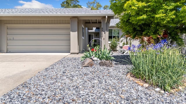 ranch-style house with roof with shingles, concrete driveway, and a garage
