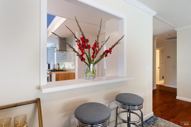 room details featuring wall chimney exhaust hood, high end stove, baseboards, wood finished floors, and ornamental molding