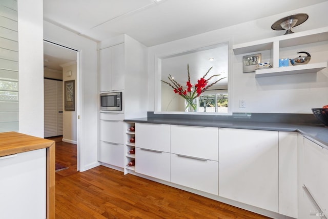 kitchen with white cabinets, stainless steel microwave, modern cabinets, and open shelves