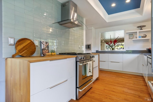 kitchen featuring wall chimney range hood, white cabinets, appliances with stainless steel finishes, tasteful backsplash, and modern cabinets