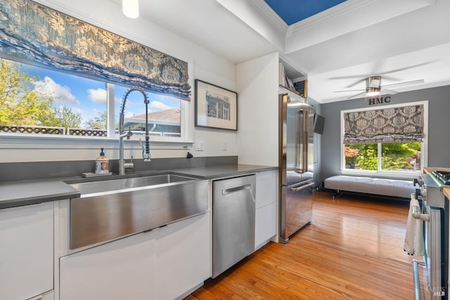 kitchen featuring a sink, stainless steel appliances, light wood finished floors, and white cabinetry