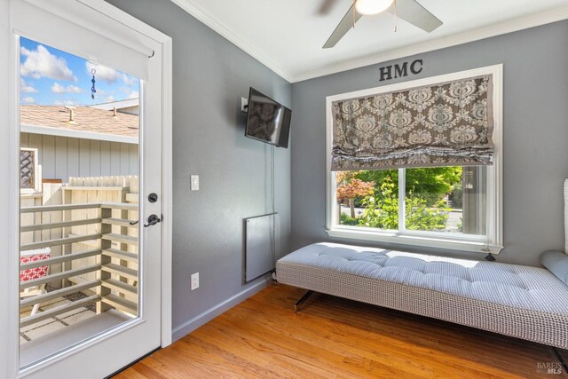 sitting room with crown molding, ceiling fan, baseboards, and wood finished floors