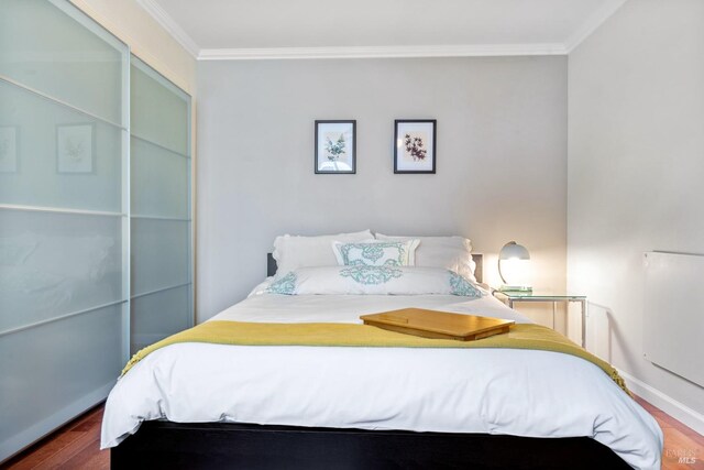 bedroom featuring baseboards, ornamental molding, and wood finished floors