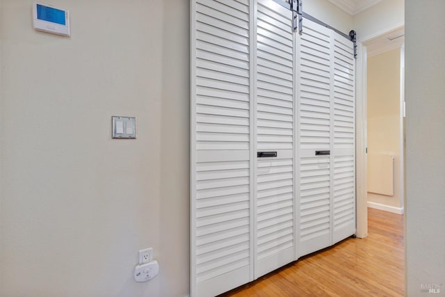 room details with a barn door, ornamental molding, and wood finished floors