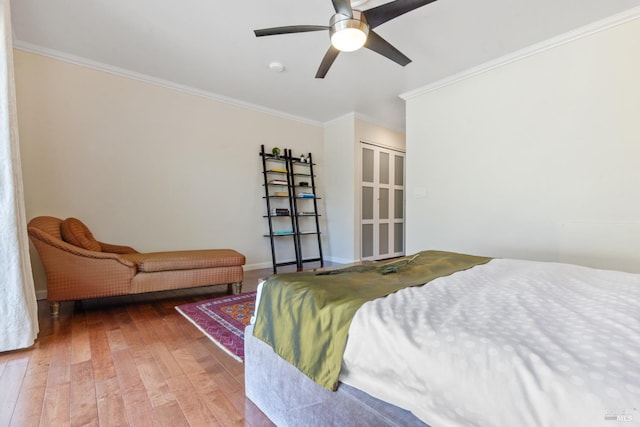 bedroom featuring wood-type flooring, ornamental molding, and a ceiling fan