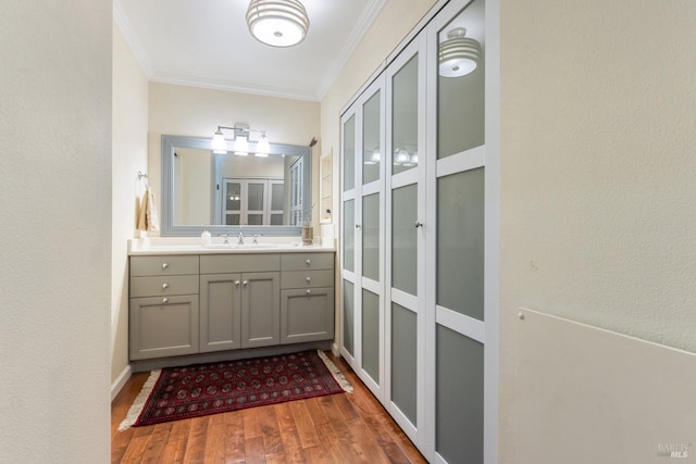 bathroom featuring crown molding, vanity, a textured wall, and wood finished floors