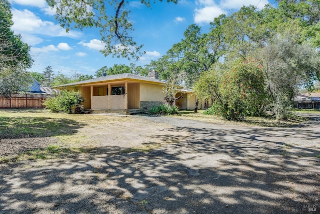 view of front of home with fence, a chimney, and driveway