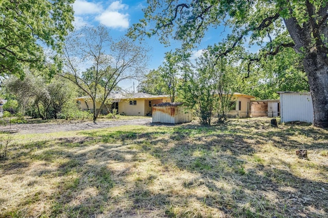 view of yard featuring a storage unit, an outdoor structure, and fence