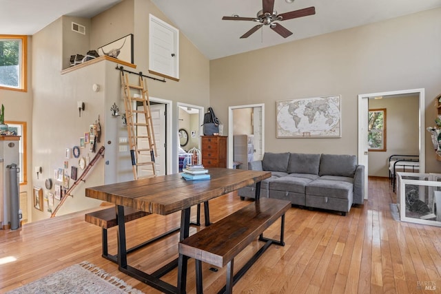 living room featuring high vaulted ceiling, visible vents, a ceiling fan, and light wood-style flooring