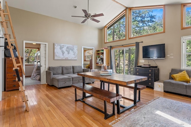 living room featuring ceiling fan, high vaulted ceiling, stairway, and light wood finished floors