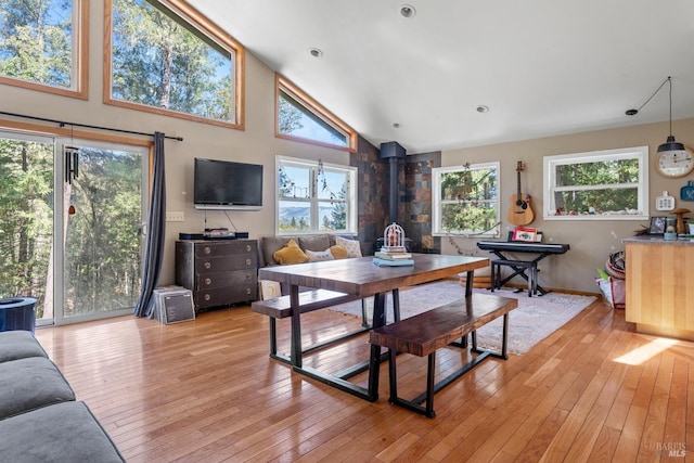 dining space featuring light wood-style flooring, high vaulted ceiling, baseboards, and plenty of natural light