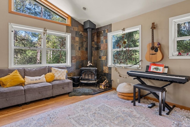 sitting room featuring wood finished floors, a wood stove, and lofted ceiling