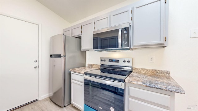 kitchen with light wood-style flooring, light stone counters, and stainless steel appliances