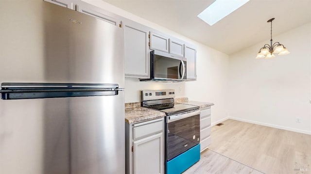 kitchen with light wood-style flooring, a skylight, appliances with stainless steel finishes, light countertops, and a notable chandelier