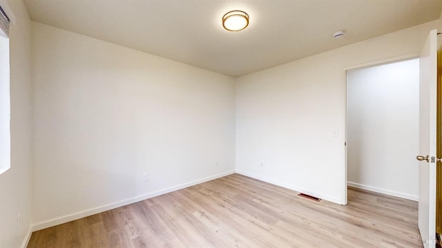 empty room featuring light wood-style flooring, baseboards, and visible vents