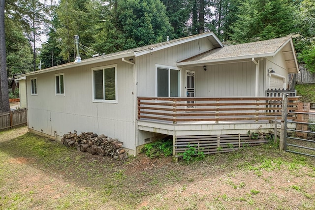 view of side of property with an attached garage, fence, and a wooden deck