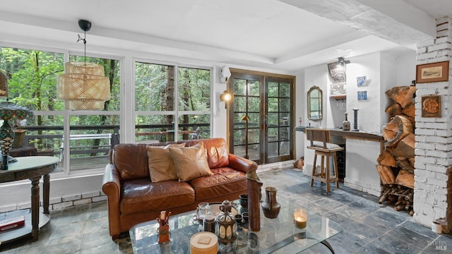 sunroom featuring a wealth of natural light, a tray ceiling, french doors, and stone tile floors