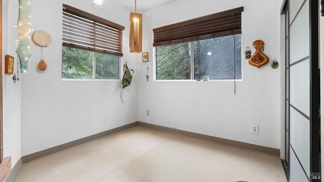unfurnished room with baseboards and concrete flooring