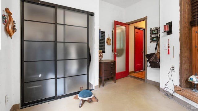 corridor featuring finished concrete flooring and baseboards