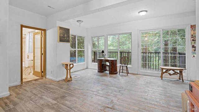 sunroom / solarium with plenty of natural light, visible vents, hardwood / wood-style flooring, and baseboards