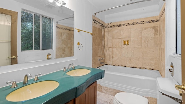 full bath with bathing tub / shower combination, double vanity, a sink, and toilet