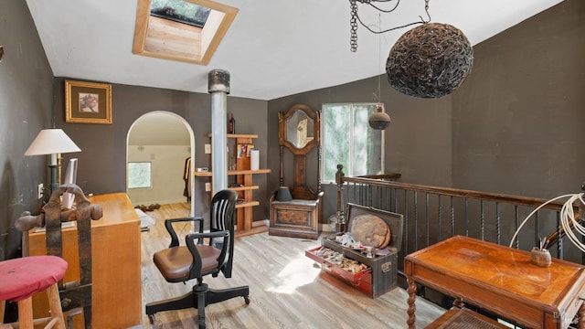 interior space featuring a wealth of natural light, arched walkways, a skylight, and wood finished floors