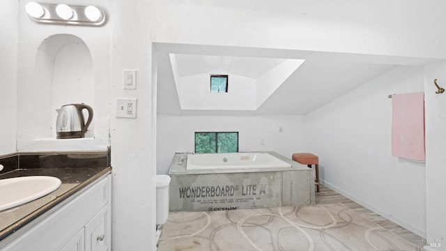 bathroom with a bath, vanity, and vaulted ceiling