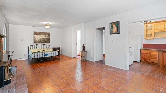 tiled bedroom with a wood stove, freestanding refrigerator, and baseboards