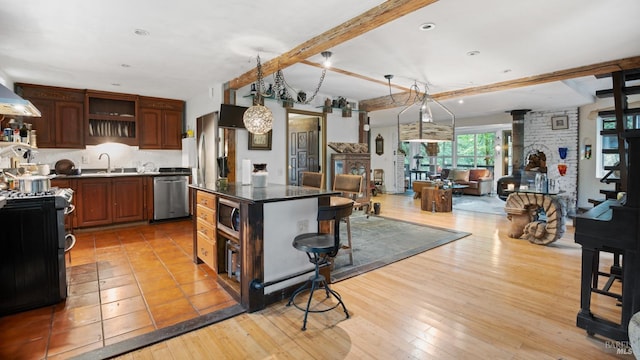 kitchen featuring open shelves, a sink, stainless steel appliances, open floor plan, and beam ceiling