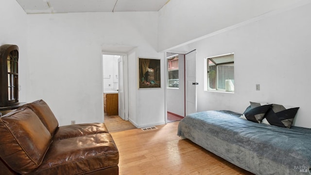 bedroom with visible vents, light wood-type flooring, and connected bathroom