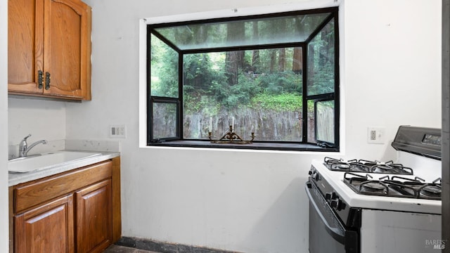 kitchen featuring white gas stove, plenty of natural light, and a sink