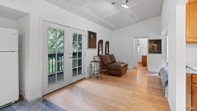 sitting room featuring french doors, light wood-style floors, and lofted ceiling