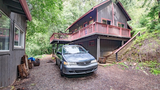 exterior space featuring a view of trees, a deck, and stairs
