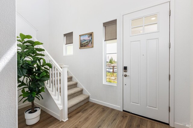 entrance foyer with baseboards, a healthy amount of sunlight, wood finished floors, and stairway