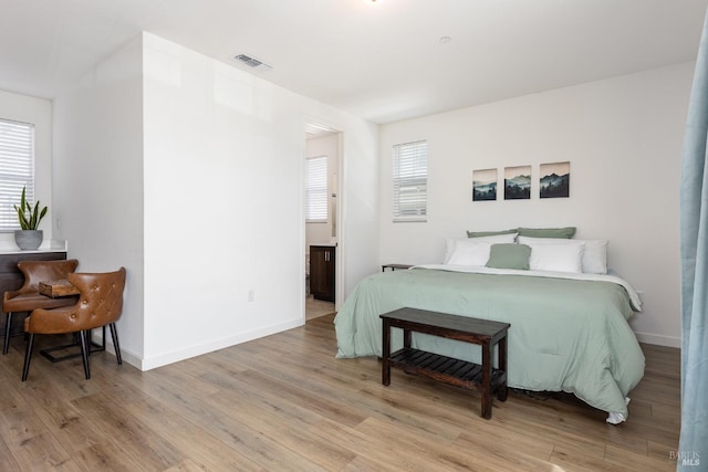 bedroom with baseboards, light wood finished floors, and visible vents