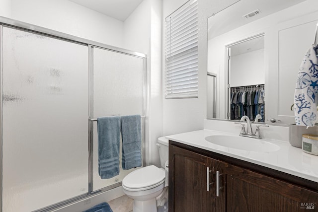 bathroom with vanity, a stall shower, toilet, and visible vents