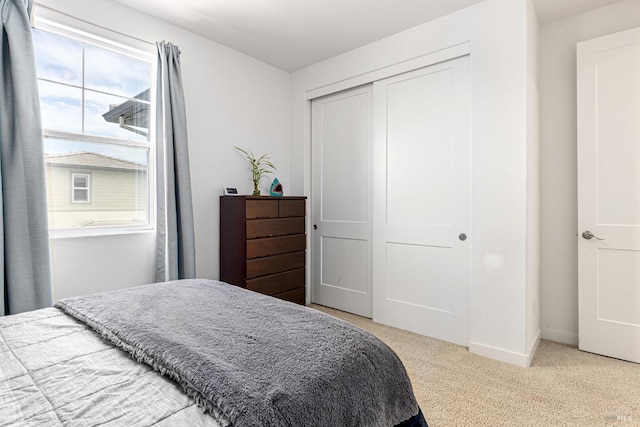 bedroom featuring baseboards, light colored carpet, multiple windows, and a closet