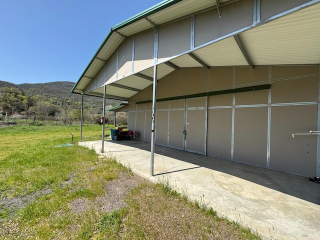 view of side of property with a mountain view and a lawn