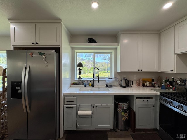 kitchen featuring a sink, light countertops, appliances with stainless steel finishes, recessed lighting, and white cabinetry