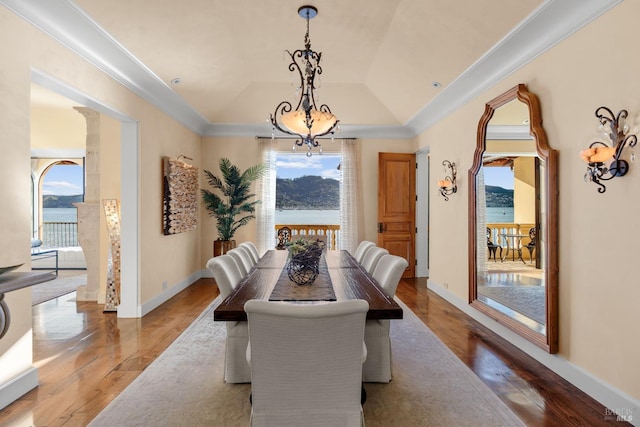 dining area with hardwood / wood-style floors, vaulted ceiling, an inviting chandelier, and a healthy amount of sunlight